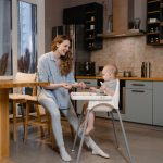 A mother and her baby enjoy bonding time in a cozy modern kitchen.