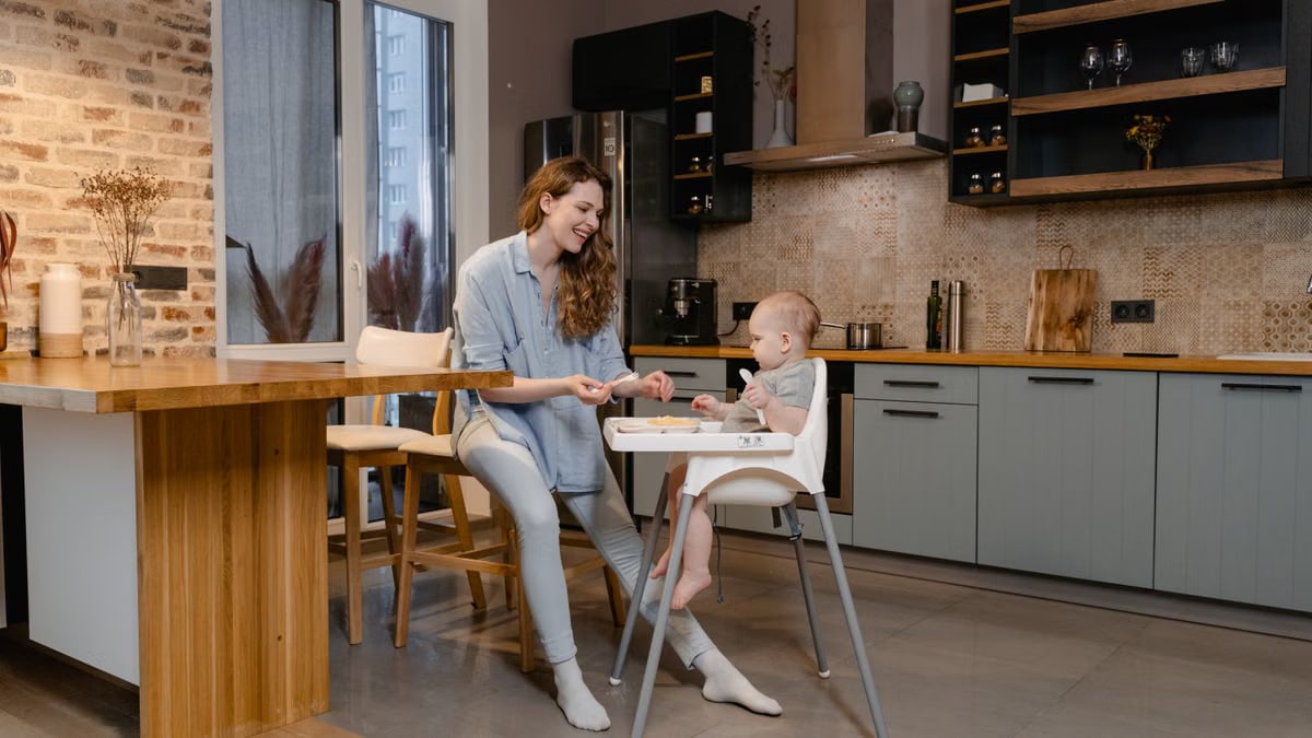 A mother and her baby enjoy bonding time in a cozy modern kitchen.