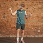 Caucasian man engaging in a jump rope workout in an indoor setting with a brick wall background.